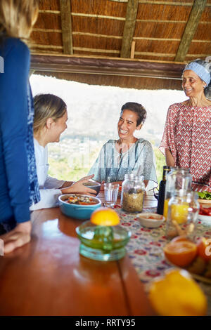 Happy friends enjoying healthy breakfast in hut during yoga retreat Stock Photo