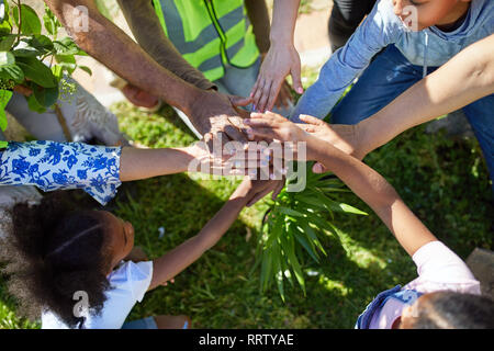Volunteers joining hands, planting trees in park Stock Photo