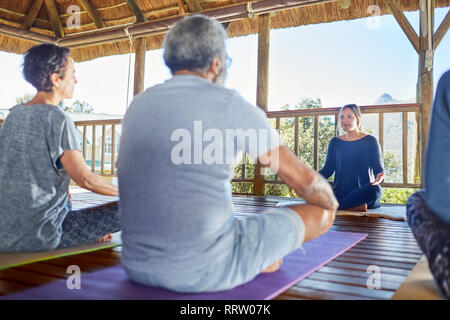 Female yoga instructor leading class in hut during yoga retreat Stock Photo