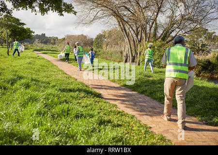 Volunteers cleaning up litter in sunny park Stock Photo