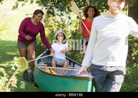 Family carrying canoe in woods Stock Photo