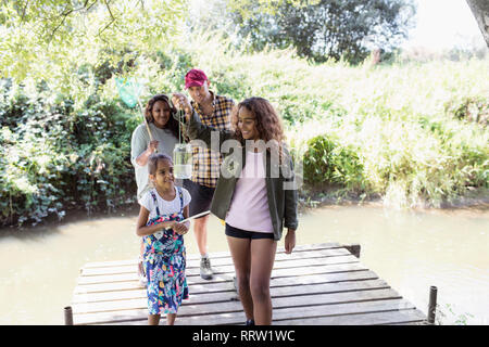 Family catching fish in jar on dock in woods Stock Photo