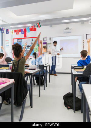 Male teacher leading lesson at projection screen in classroom Stock Photo
