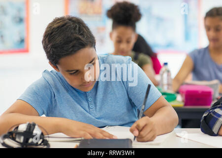 Junior high school boy student doing homework in classroom Stock Photo