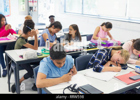 Junior high school students studying at desks in classroom Stock Photo