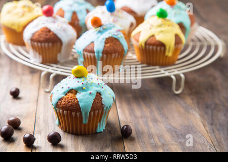 Easter or birthday cupcakes glazed with colorful sugar, sprinkles and chocolate for a kids party on a rustic wooden table Stock Photo