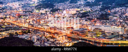 Business concept, tilt shift effect modern cityscape of nagasaki dusk from mount inasa, the new top 3 nightview of the world, aerial view, copy space Stock Photo