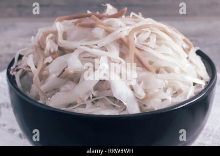 In a ceramic Cup on an old wooden table sauerkraut with carrots. Close up. Stock Photo