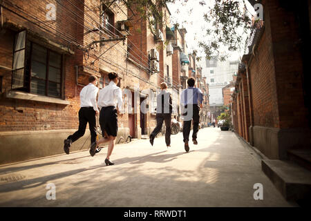 Four business colleagues running together down a city street. Stock Photo