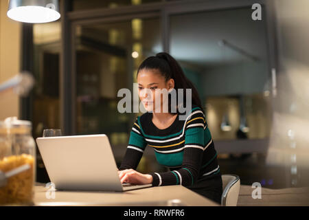 Focused woman using laptop at home at night Stock Photo