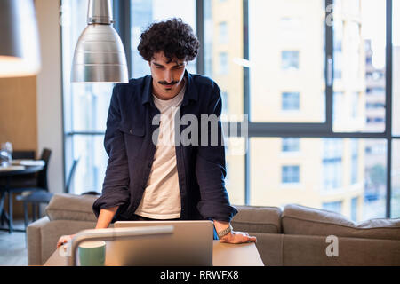Man using laptop in urban apartment kitchen Stock Photo
