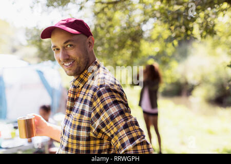 Portrait happy man drinking coffee at sunny campsite Stock Photo