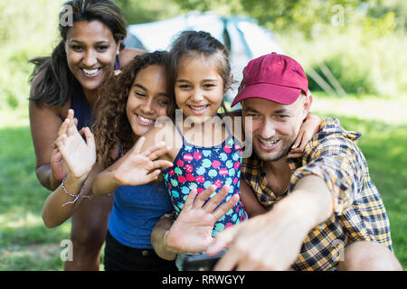 Happy family waving, taking selfie with camera phone at campsite Stock Photo