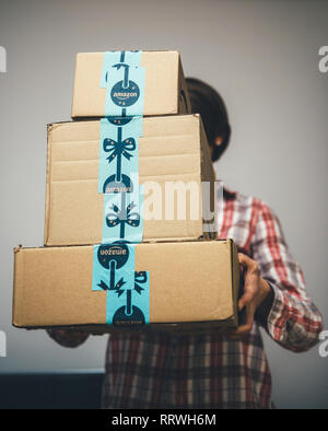 PARIS, FRANCE - DEC 2, 2018: Young woman holding three Amazon Prime parcel cardboard box stack one above another ready for winter holidays gifts shopping - on time delivery Stock Photo