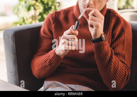 cropped view of man smoking cigarette in cafe Stock Photo