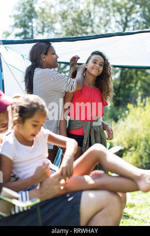 Mother fixing daughters hair at campsite Stock Photo