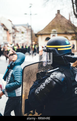 Proestor Shield A protester wearing a yellow safety vest and a respirator holds a ...
