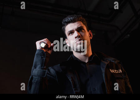 handsome guard in black uniform holding flashlight Stock Photo