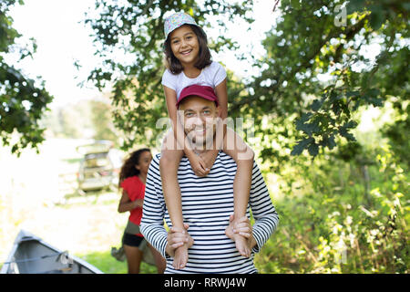 Portrait father carrying daughter on shoulders in woods Stock Photo