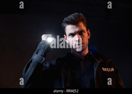 guard in uniform holding flashlight and looking at camera Stock Photo