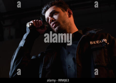 guard in uniform holding flashlight and looking away Stock Photo