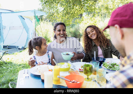 Happy family enjoying lunch at campsite table Stock Photo