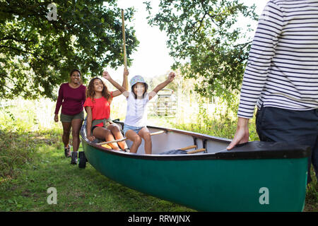 Excited family carrying canoe in woods Stock Photo