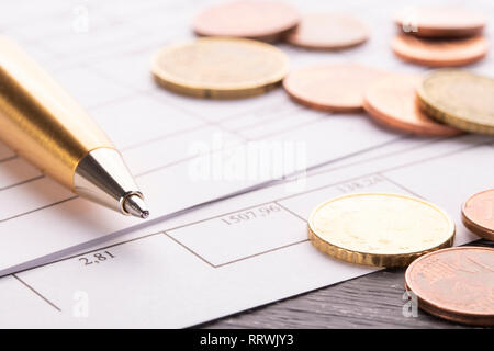 Stack of euro euro coins on old black wooden table. Pen and accounting documents with numbers. Payment planning utility bills Stock Photo
