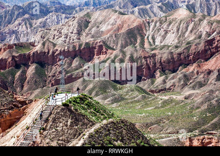 Couple of Chinese Tourists are Taking Pictures in a Viewing Platform on Top of the Mountain in Binggou Danxia Canyon Landform in Zhangye, Sunan Region Stock Photo