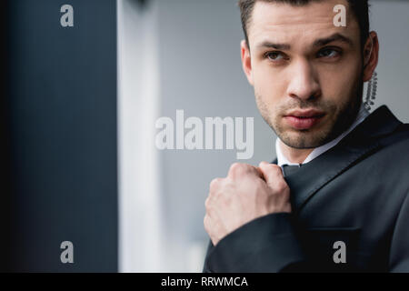 thoughtful bodyguard in suit using earphone Stock Photo