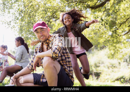 Happy daughter running to hug father at campsite Stock Photo