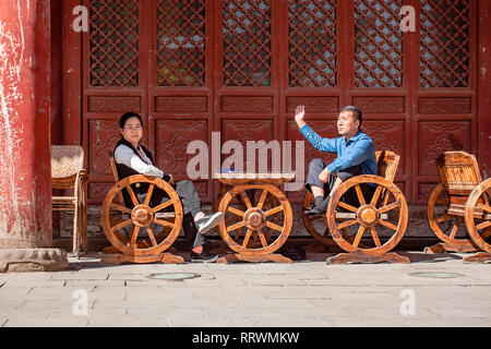 Asian Couple Sitting And Chatting Outside. Chinese Wife And Husband Are Having Conversation On A Street. Stock Photo