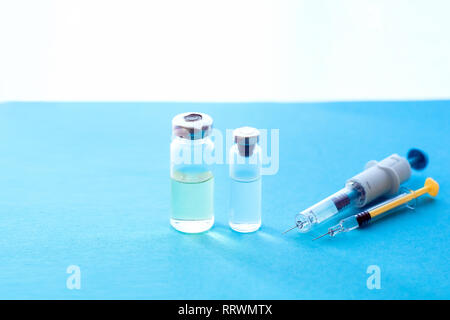 Syringes, medicine bottles on a blue background. Vaccination concept Stock Photo