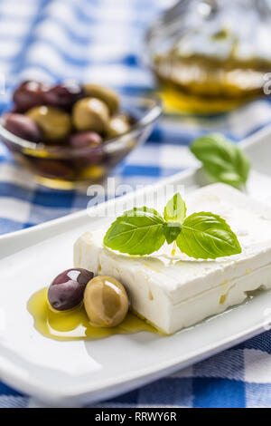 Greek cheese feta with olive oil olives and basil leaves.