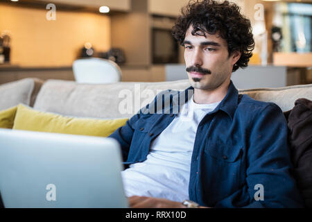 Man using laptop on sofa Stock Photo