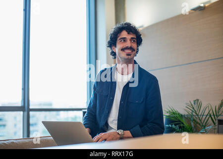 Smiling man using laptop at home Stock Photo
