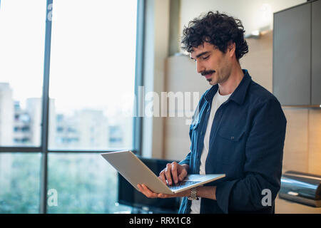 Man using laptop in apartment Stock Photo
