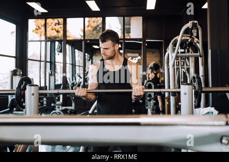 Young guy with muscular body with barbell in a gym. - Image Stock Photo