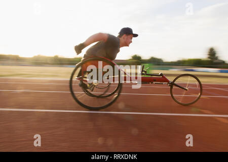 Teenage boy paraplegic athlete speeding along sports track in wheelchair race Stock Photo