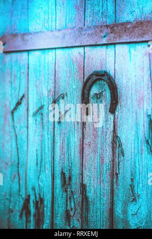 Old metal horseshoe hanging on blue wooden door Stock Photo