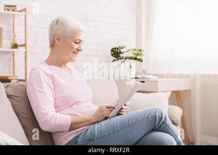 Smiling beautiful senior woman using digital tablet Stock Photo