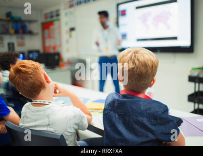 Junior high school boys watching teacher during lesson in classroom Stock Photo