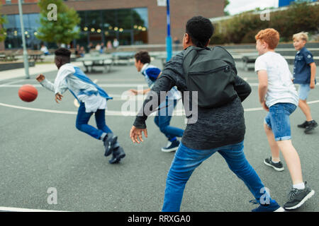 Junior high boy students playing basketball in schoolyard Stock Photo