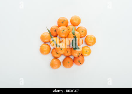 top view of bright ripe orange tangerines with green leaves stacked in pile on white background Stock Photo
