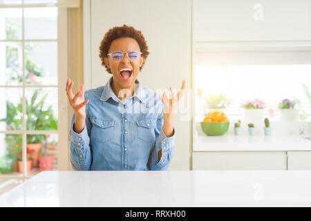 Young beautiful african american woman wearing glasses celebrating mad and crazy for success with arms raised and closed eyes screaming excited. Winne Stock Photo