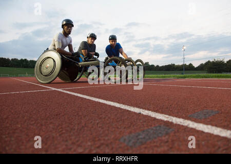 Portrait determined paraplegic athletes training for wheelchair race on sports track Stock Photo
