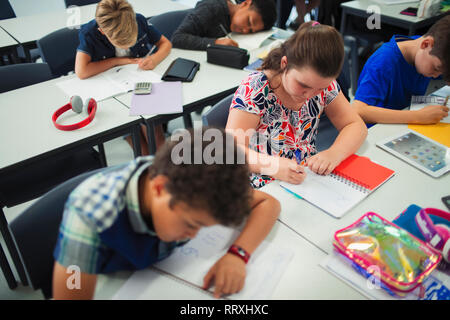 Junior high school students doing homework at desks in classroom Stock Photo
