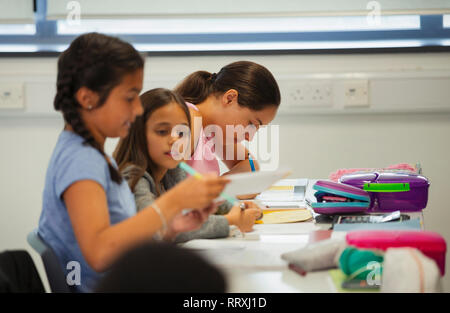 Junior high school girl students studying at desk in classroom Stock Photo