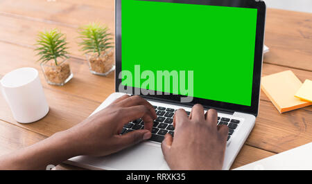 Millennial man working on laptop with blank green screen Stock Photo