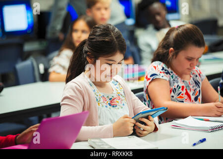 Focused junior high school girl student using digital tablet in classroom Stock Photo